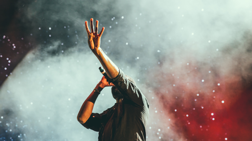 person singing on stage surrounded by smoke